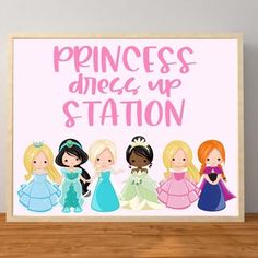 princesses dress up station sign on a wooden table next to a white wall with pink lettering