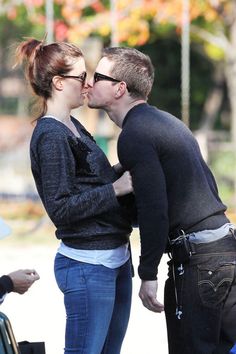 a man and woman kissing each other on the street