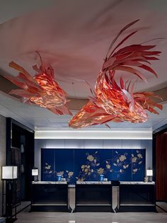 an artisticly designed room with blue walls and artwork on the ceiling, along with two large fish sculptures