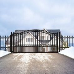 an iron gate in front of a house with snow on the ground and blue sky