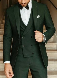 a man in a green suit and bow tie is standing on stairs with his hands in his pockets