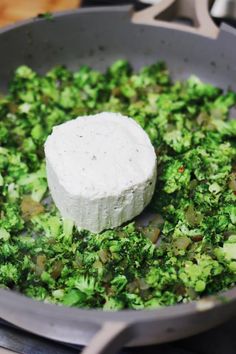 a pan filled with broccoli and cheese on top of a stove burner