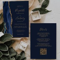 an elegant wedding suite with gold foil and navy blue color palettes is displayed on a table