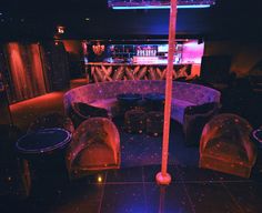 a dimly lit room with chairs, tables and an umbrella on the floor in front of a bar