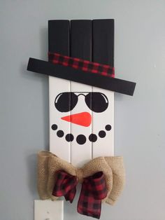 a snowman with sunglasses and a bow tie hanging on a wall in front of a light switch