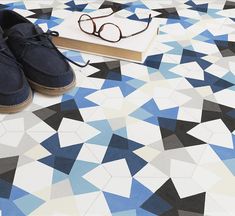 a pair of shoes sitting on top of a blue and white floor next to a book