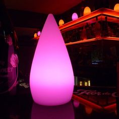 a pink light sitting on top of a table next to a bottle of booze