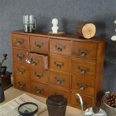 an old wooden cabinet with many drawers and knobs on the top, next to a newspaper