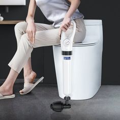 a woman sitting on top of a toilet with her foot propped against the tank lid