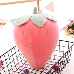 a strawberry shaped pillow sitting on top of a metal basket