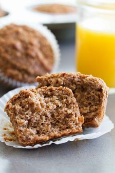 two muffins sitting on top of paper plates with orange juice in the background