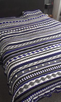 a bed with a blue and white crocheted coverlet on top of it