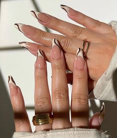 a woman's hand with long, shiny nails and gold rings on her fingers