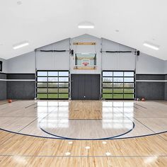 an indoor basketball court with hard wood flooring and glass doors leading into the gym