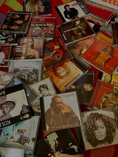 a pile of various cd's sitting on top of a red table next to each other