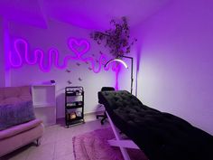 a room with purple lighting and a black bench in the corner, next to a pink chair