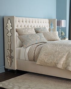 a bedroom with blue walls and a white bed in the middle is decorated with silver accents