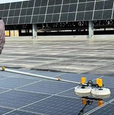 a man standing on top of a roof next to a solar panel with two wheels