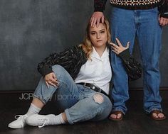 a woman sitting on the floor next to a man with her hands behind her head