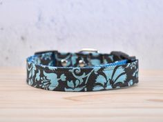 a blue and black floral dog collar on a wooden table