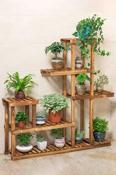 a wooden shelf filled with potted plants on top of a tiled floor next to a wall