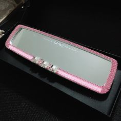 a pink and silver tray sitting on top of a black table next to a mirror