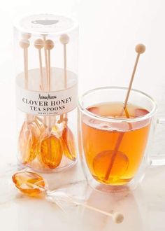 a glass cup filled with tea next to a box of honey sticks