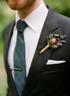 a man wearing a suit and tie with a boutonniere on his lapel