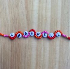 the word chapel spelled with beads on a wooden surface