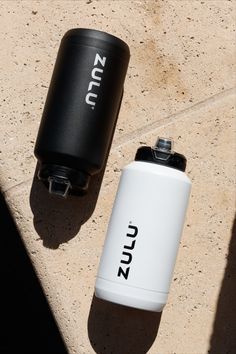 two black and white flasks sitting next to each other on the ground,