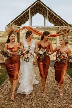 three bridesmaids walking down the aisle with their bouquets in hand and wearing orange dresses