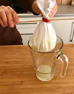 a person holding a cloth in a glass cup on a wooden table with a wood counter top