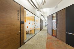 an office hallway with wooden doors and decorative wallpaper on the walls, along with glass partitions