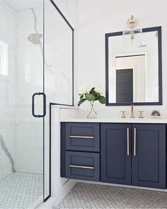 a white and blue bathroom with marble counter tops, double sink, and shower stall