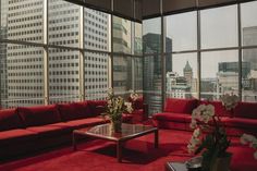 a living room filled with red couches next to tall buildings in the city skyline