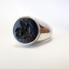 Embrace mythical elegance with our handmade Glass Intaglio Pegasus Ring, crafted in sterling silver. This exquisite piece combines the allure of ancient mythology with contemporary craftsmanship, making it a unique addition to your jewelry collection. Meterial : 925K solid Silver Stone : Glass İntaglio  Stone Dimensions : 15 x 15 mm Ring Band Wide: 16 to 5 mm Weights : Silver : 10.72 gr.  Please Contact With Me if You any order Requested. Symbolic Intaglio Engraved Ring, Silver Intaglio Symbolic Ring, Silver Symbolic Intaglio Ring, Symbolic Silver Intaglio Ring, Symbolic Silver Ring With Intaglio Detail, Silver Signet Ring With Intaglio, Silver Round Signet Ring With Intaglio, Vintage Sterling Silver Intaglio Ring, Man Ring