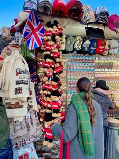 a woman standing in front of a store selling hats and scarves