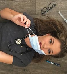 a woman with a medical mask and stethoscope laying on the floor next to her