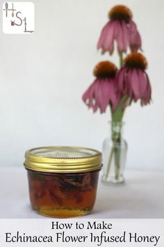 a jar filled with honey next to some flowers