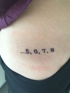 the back of a woman's stomach with numbers tattooed on it