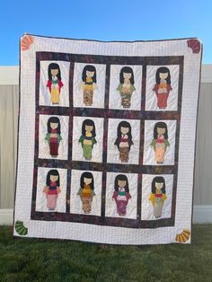 a quilted wall hanging on the side of a fence in front of a white fence