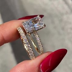 a close up of a person holding a ring with a princess cut diamond on it