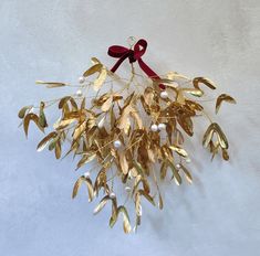 a bunch of gold leaves with a red ribbon hanging from it's centerpiece