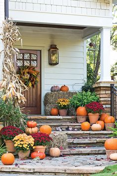 pumpkins and gourds decorate the front steps of a house