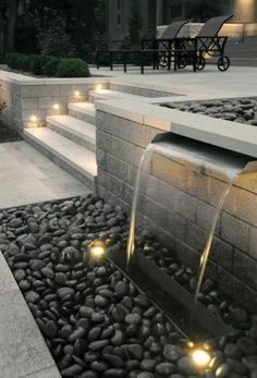 an outdoor fountain with lights on it and some steps leading up to the water feature