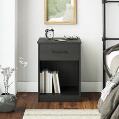 a nightstand with two books on it next to a bed