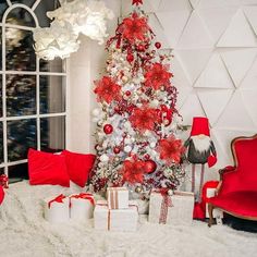 a decorated christmas tree in a living room with red and white decorations on the walls