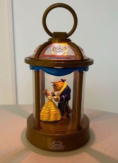 the beauty and the beast figurine is under a glass dome