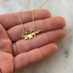 This necklace features a solid brass oak leaf pendant gracefully suspended on a 14k gold fill chain. The oak leaf's timeless design and warm brass hue offer a touch of natural charm. With a clean and minimalist aesthetic, the necklace embraces simplicity, allowing the intricate details of the oak leaf to shine. The 14k gold fill chain adds a hint of elegance, creating a seamless fusion of classic and contemporary style. Durable and versatile, this necklace is a celebration of the enduring beauty found in the simplicity of nature. ● 16" Chain ● 14k Gold fill chain ● Solid Brass Oak Leaf Oak Leaf Necklace, Oak Leaf, Women's Jewelry And Accessories, Leaf Necklace, Leaf Pendant, Minimalist Aesthetic, Gold Filled Chain, Language English, Intricate Details