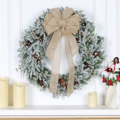 a christmas wreath on a mantle next to candles